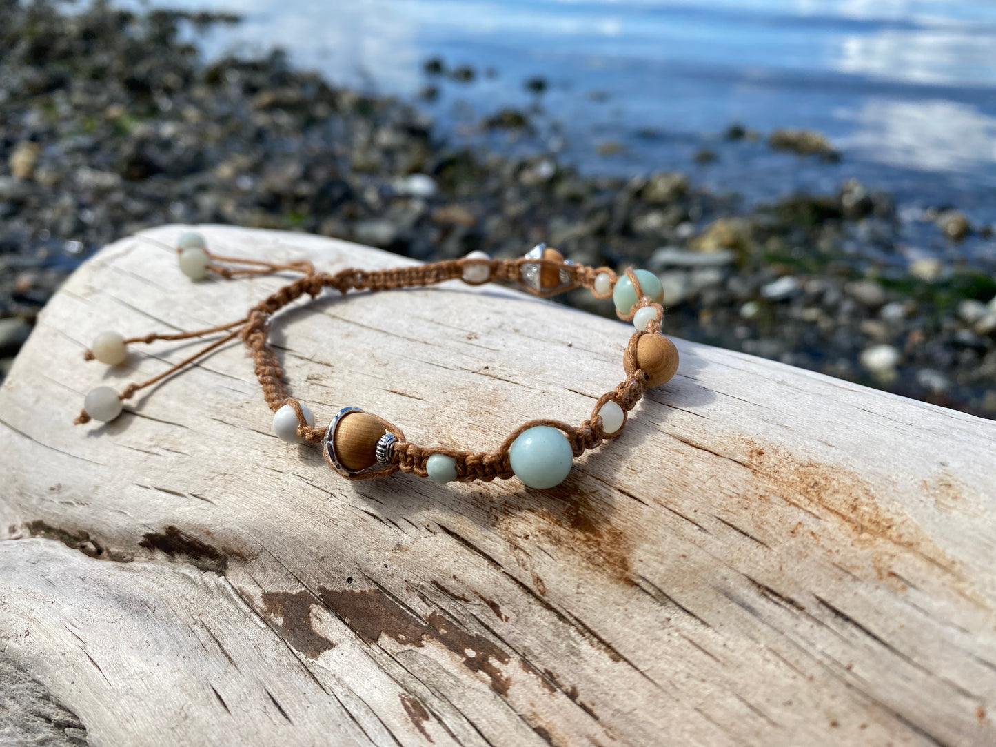 Beautiful Boho Braided Rustica Bracelet for any beach girl, sitting on a piece of driftwood with the ocean in the background