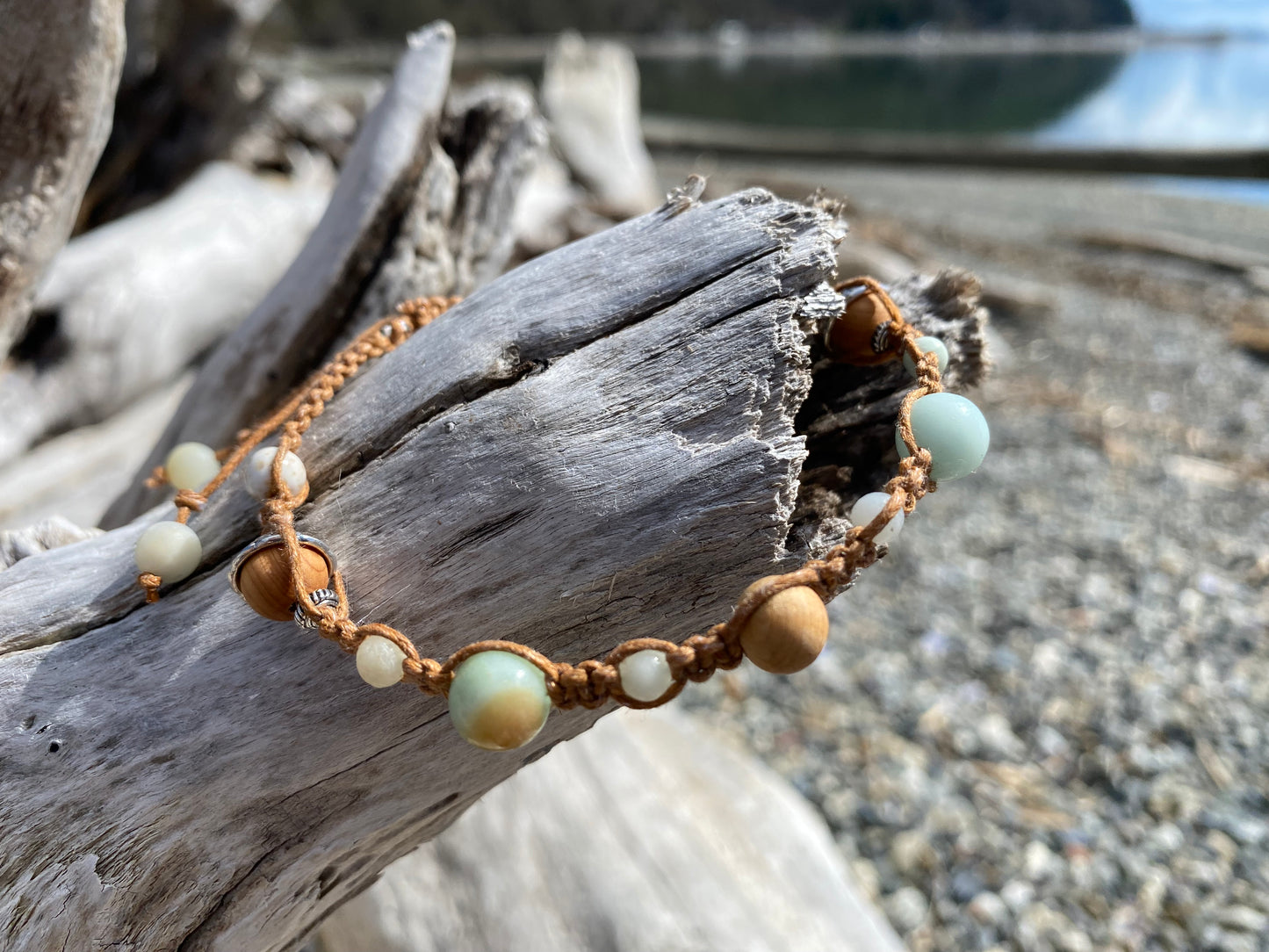 Beautiful Boho Braided Rustica Bracelet for any beach girl, sitting on a piece of driftwood with the ocean in the background